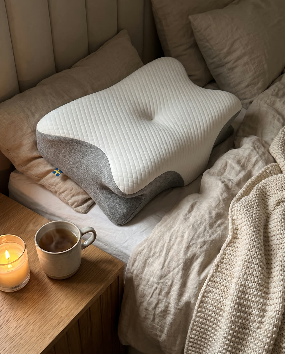 SleepEase sovepude på seng med strikket plaid og te på natbordet